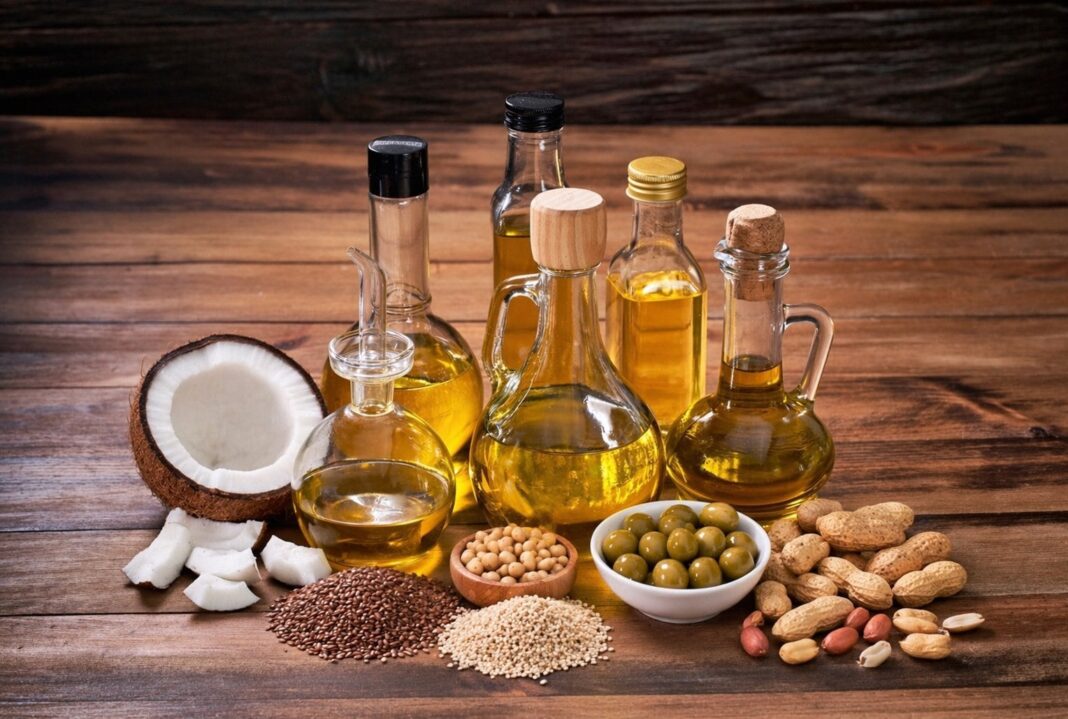Botellas de diferentes aceites vegetales saludables, como oliva, coco y girasol, sobre una mesa de cocina.