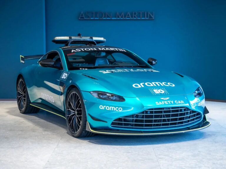 Aston Martin Vantage Safety Car de Fórmula 1 estacionado en un box, con la decoración oficial y luces encendidas.