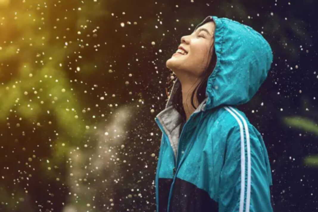 Persona observando la lluvia desde un refugio, ilustrando el tema de los efectos de la lluvia en el estado de ánimo.