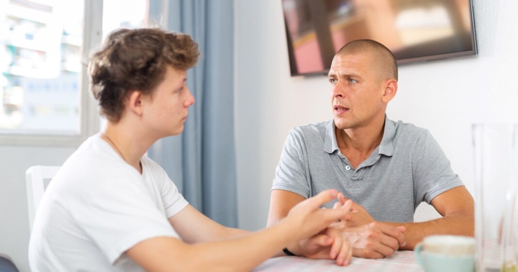 Padre y adolescente teniendo una conversación seria y respetuosa en un entorno familiar.
