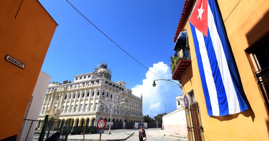 Bandera de Cuba ondeando frente a un edificio gubernamental.