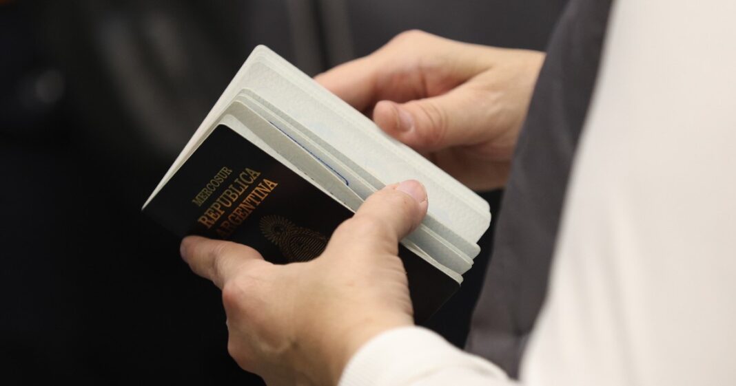 Pasaporte estadounidense abierto sobre una superficie, junto a un teléfono móvil que simboliza la digitalización del control migratorio