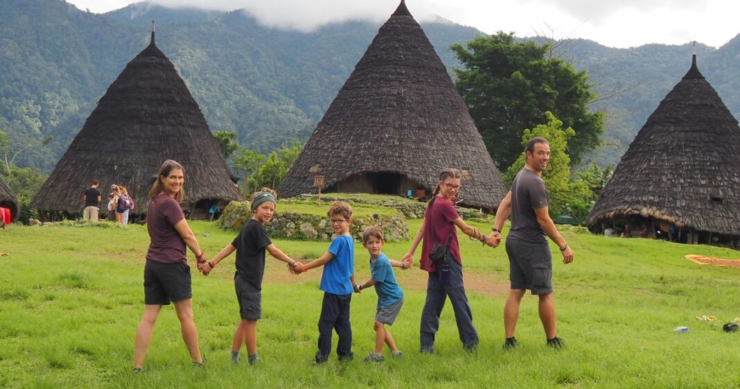 Familia Pelletier Lemay sonriendo durante un viaje, con un paisaje de montaña al fondo.