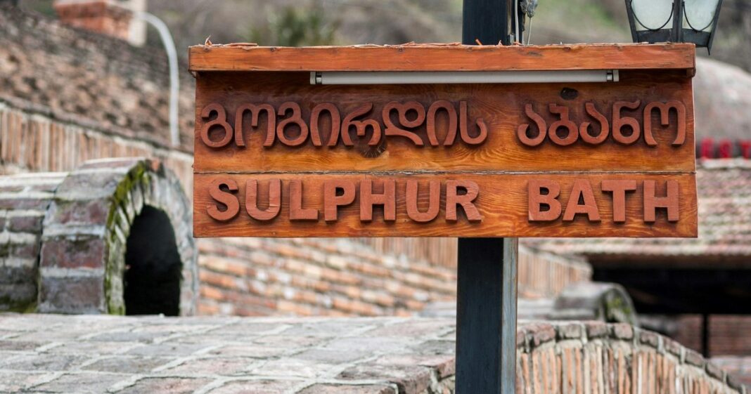 Ejemplo de escritura en alfabeto georgiano Mxedruli junto a su transliteración