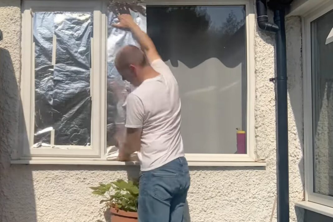 Ventana cubierta con papel aluminio para reflejar el calor del sol y refrescar el interior de una habitación.