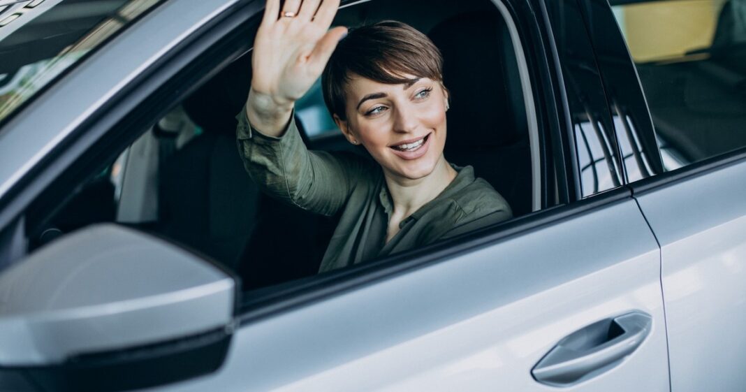 Conductor manejando un auto con el brazo izquierdo apoyado fuera de la ventanilla.
